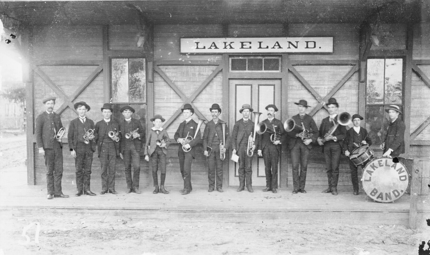 Members of the Lakeland Brass band wait at the train station in Lakeland, Florida to greet the train carrying President Grover Cleveland, 1895; link to "Sounds of Music" Flickr album