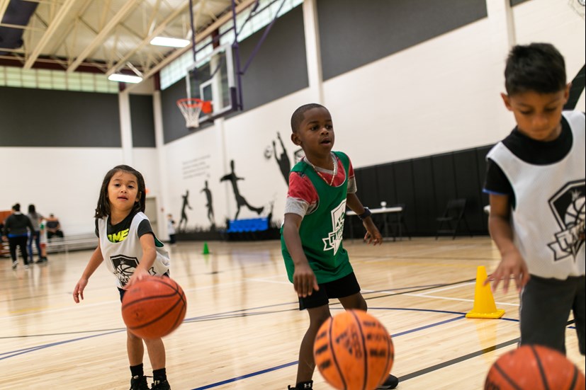 Three small children dribbling basketballs.