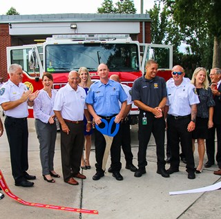 Dignitaries and design committee members cutting ribbon for new fire engine 51