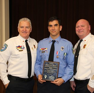 Driver Engineer Harvey Ries photographed with his award, flanked by Fire Chief Douglas E. Riley and Assistant Chief Michael Williams.