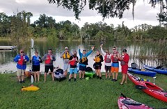 Excited group of kayakers cheer and give thumbs up on the shore of Lake Crago