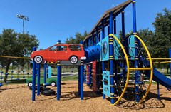 John McGee Park playground with colorful playpieces and a car theme going throughout