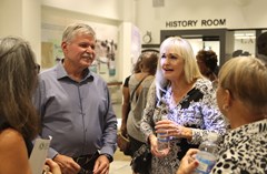Group of people standing together and talking in Lakeland History & Culture Center exhibit room with History Room sign in the background