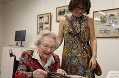 Two women, one standing, one seated, examining photo albums in the Lakeland History Room