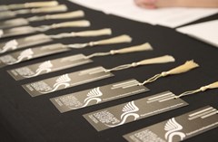 Tassled bookmarks with Lakeland History & Culture Center swan logo displayed individually on black tabletop