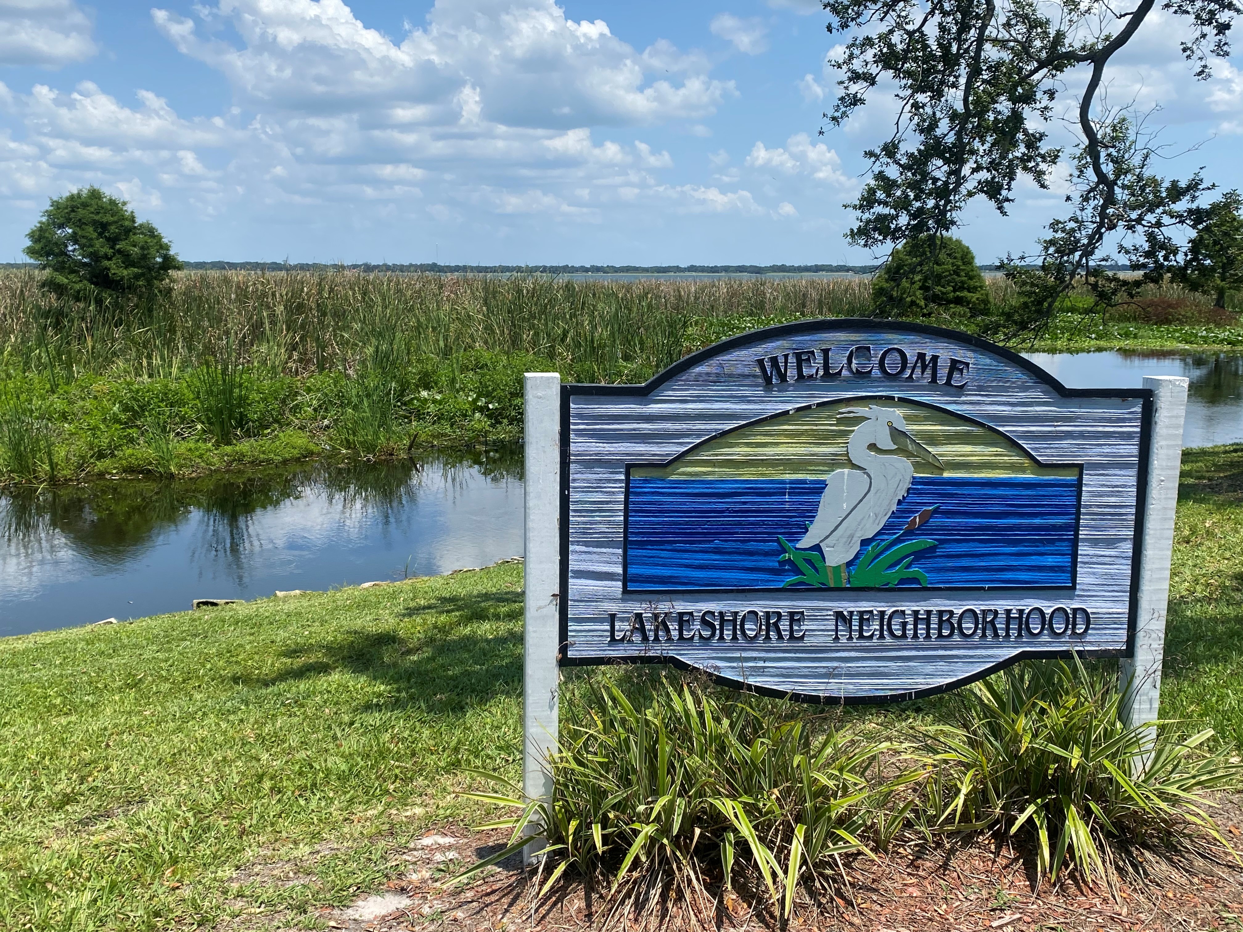 A sign welcoming you to the Lakeshore Neighborhood, sitting in front of Lake Parker.