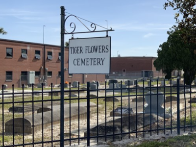 View into Tiger Flowers Cemetery with sign and wrought iron gate surround; link to Google map to Tiger Flowers Cemetery