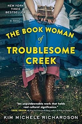 Book cover of The Book Woman of Troublesome Creek by Kim Michele Richardson. Cover features image of a woman in a dress and brown boots seated with a tied stack of books in her lap.