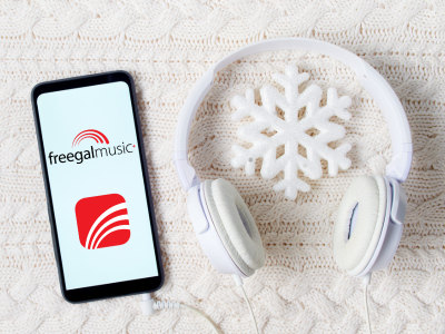 Freegal music+ logo and icon a cell phone screen with white sweater background, white headphones, and snowflake.