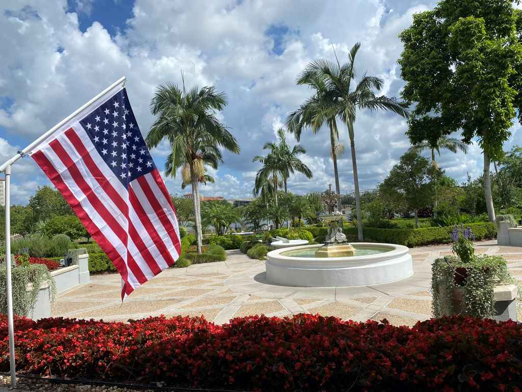 View of Hollis garden with a fountain in teh background and an American Flag displaying prominently in the foreground to the left