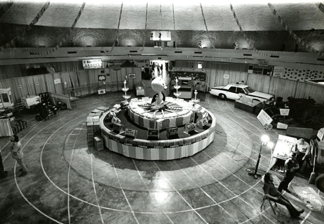 Overhead view of the main display area of the 1975 Citrus Showcase and Expo in Winter Haven.  At the center is a large replica of the Orange Bird; link to "Lakeland Ledger" contentDM collection