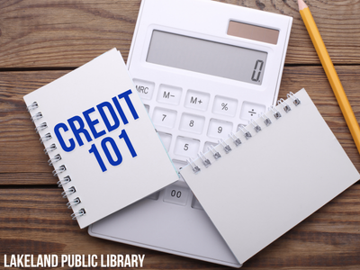 Calculator, pencil, and two small open spiral-bound notebooks on wooden background with text "Credit 101, Lakeland Public Library"