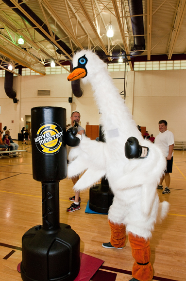 Person dressed in swan costume punching a bag in a basketball gym