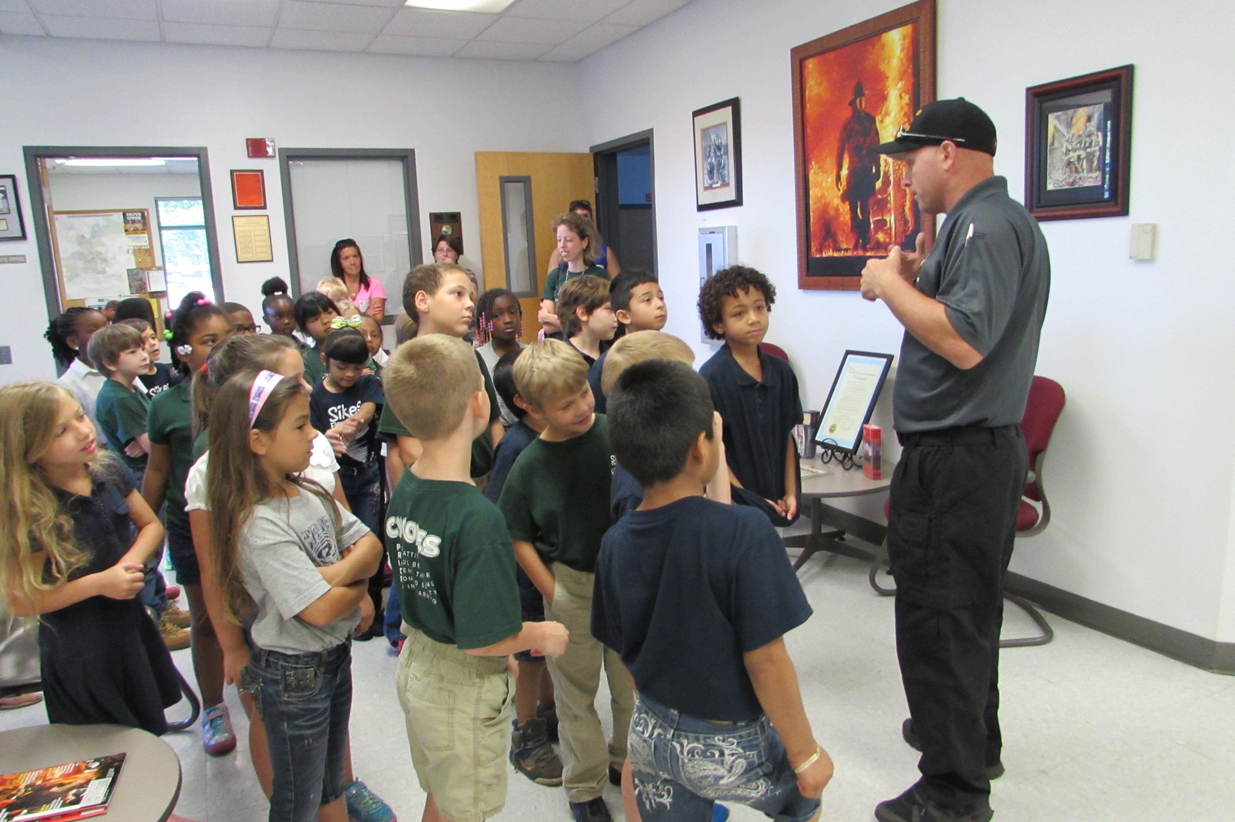 A photo of a fire fighter talking to students during a station tour