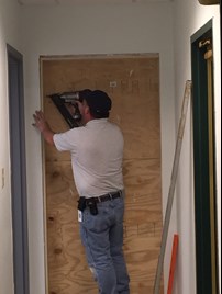 An employee boarding up a wall with a nail gun.