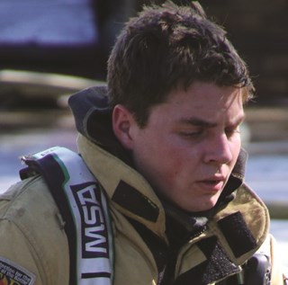 Exhausted Firefighter, kneeling, after Structure Fire